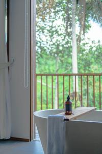 uma banheira na casa de banho com uma janela em LeRosa Valley Resort em Ubud