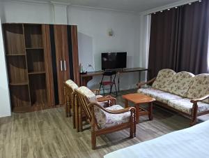 OYO 90809 Oriental Hotel في Sarikei: غرفة في الفندق تحتوي على أريكة وكراسي وتلفزيون
