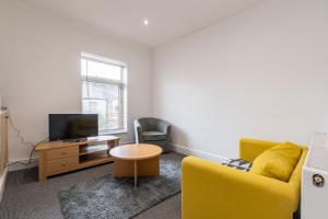 a living room with a yellow couch and a tv at Chesterfield Lodge - 2 Bedroom Apartment near Chesterfield Town Centre in Chesterfield