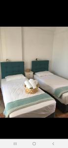 two beds with white sheets and a basket on them at Marili Apartments in Roda