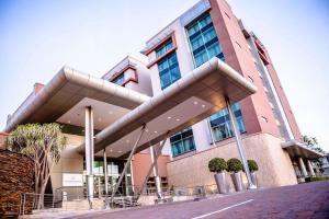 un grande edificio con alberi di fronte di Southern Sun Rosebank a Johannesburg