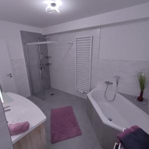 a bathroom with a tub and a shower and a sink at Ferienapartment 21 in Kurort Gohrisch +19 photos