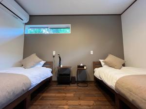 une chambre avec deux lits et une fenêtre sur le mur dans l'établissement BETSUINN MINI, à Hakuba