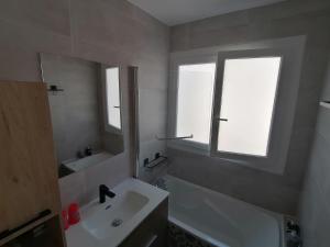 een badkamer met een wastafel, een bad en een spiegel bij appartement 50 m2 vue mer in Villers-sur-Mer