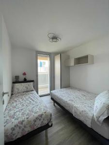 a bedroom with two beds and a window at MARE Appartamento 8 in Lignano Sabbiadoro