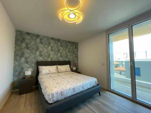 1 dormitorio con cama y ventana grande en MARE Appartamento 8 en Lignano Sabbiadoro