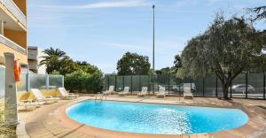 a swimming pool in a courtyard with lounge chairs at Résidence Pierre & Vacances La Rostagne in Juan-les-Pins