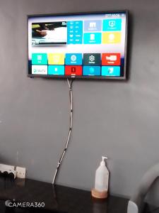 TV de pantalla plana colgada en la pared con una botella de leche en Backpackers at Banana Hill, en Nairobi
