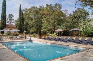 a swimming pool with chairs and tables and trees at Château Lamothe in Baziège