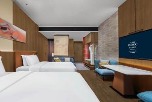 a hotel room with two beds and a tv at Hotel Indigo Changsha Meixi Lake in Changsha