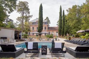 a swimming pool with chairs and a building at Château Lamothe in Baziège