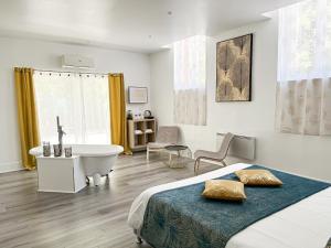 a bedroom with a bed and a tub and a sink at Ch&acirc;teau Lamothe in Bazi&egrave;ge