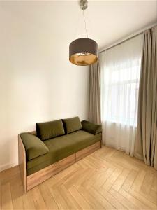 a living room with a green couch in front of a window at Picturesque Old Town Apartment with Charming Balcony in Kaunas