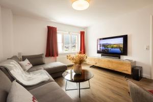a living room with a couch and a flat screen tv at Alpin Supreme in Oberstdorf