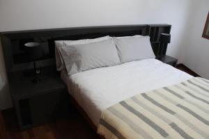 1 cama con sábanas blancas y almohadas en una habitación en Apartamentos Camino Inglés, en Ordes