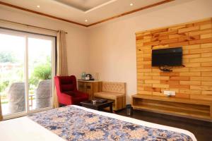 a bedroom with a bed and a tv and a chair at DESI THATH RESORT in Alwar