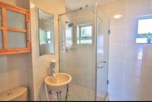 a white bathroom with a sink and a shower at Holiday house on the beach in Kingsborough