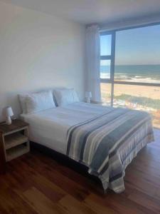 a bedroom with a bed with a view of the beach at Holiday house on the beach in Kingsburgh