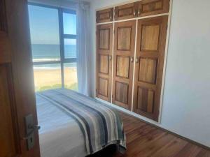 a bedroom with a bed with a view of the beach at Holiday house on the beach in Kingsborough