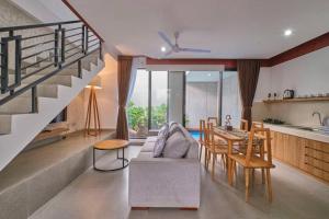 uma sala de estar com uma escada e uma mesa e cadeiras em Lavilla B1 New-3BR Pool Villa 15 Mins from Ubud Centre em Ubud