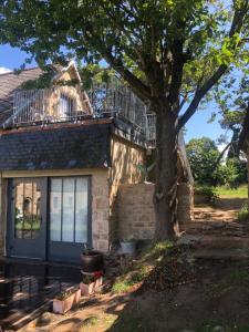 a house with a balcony and a tree in front of it at Les écolodges Sous Le Phare in Louannec