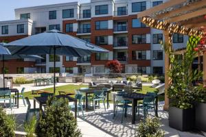 an outdoor patio with tables and chairs and an umbrella at Brighton 2br w wd gym nr Green Line BOS-894 in Boston