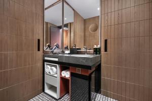 ein Bad mit einem Waschbecken und einem Spiegel in der Unterkunft Hotel Indigo Changsha Meixi Lake in Changsha