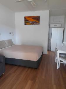 a small bedroom with a bed and a table at Aromet Motor Inn in Temora