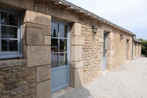 un edificio de piedra con una puerta y ventanas azules en Pierres Blanches Guérande - Maison d'hôtes en Guérande