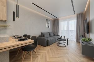 eine Küche und ein Wohnzimmer mit einem Sofa und einem Tisch in der Unterkunft Exclusive Apartment with Balcony & Parking Wrocław by Renters Prestige in Breslau