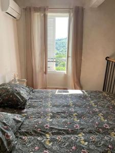 a bedroom with a bed and a window with a bedspread at Appartement de type duplex in Callian