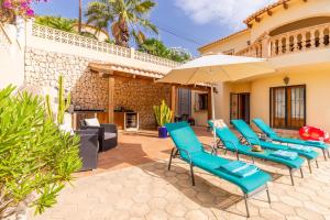 un patio con sillas azules y una sombrilla en Villa Rafael, en Cumbre del Sol