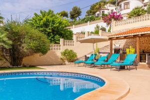 Villa con piscina y tumbonas azules en Villa Rafael en Cumbre del Sol