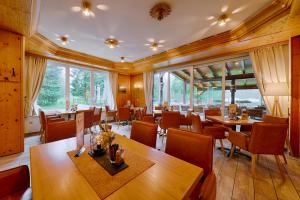 um restaurante com mesas e cadeiras de madeira e janelas grandes em Tanzbuche em Friedrichroda