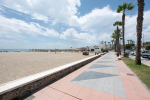 a sandy beach with palm trees and a sidewalk at Casa Beramendi in Torremolinos