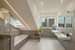 a bathroom with two sinks and a bath tub and a tubermott at SweetHome - Poing Apartments in Poing