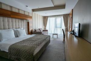 ノヴィサドにあるGarni Hotel Centarのベッドとテレビが備わるホテルルームです。