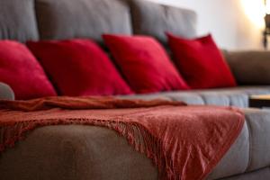un sofá con almohadas rojas y una manta roja. en Second line Puerto Banús top floor en Marbella