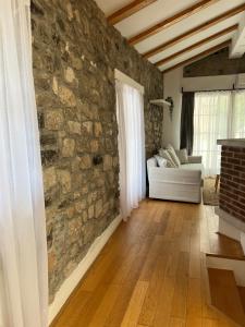 a living room with a stone wall and a white couch at Guesthouse 45 in Dutovlje
