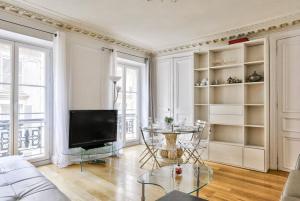 ein Wohnzimmer mit einem TV und einem Tisch in der Unterkunft Appartement Quartier Champs-Élysées 3 in Paris