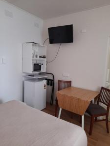 Habitación pequeña con mesa y TV en la pared. en Aromet Motor Inn, en Temora