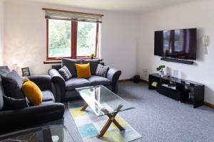 uma sala de estar com dois sofás e uma televisão em Bothwell Court Apartments em Dunfermline