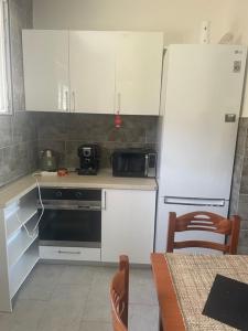 uma cozinha com armários brancos, um frigorífico e uma mesa em Villa Nilić em Bar