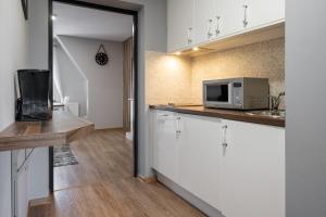 een keuken met witte kasten en een magnetron bij RentPlanet - Apartament Antałówka in Zakopane