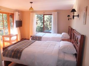 a bedroom with three beds and a window at Casona el Sauce in Curicó