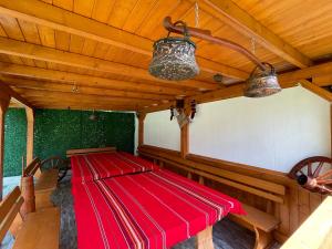 eine Holzterrasse mit einem roten Tisch und zwei Lichtern in der Unterkunft Villa Stoyanovata Kashta in Samokow