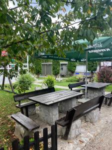 a picnic table and benches in a park at Rooms and Apartments Neron Bihać in Lohovo