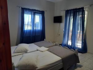 2 camas individuales en un dormitorio con cortinas azules en Viviana House, en Mitikas