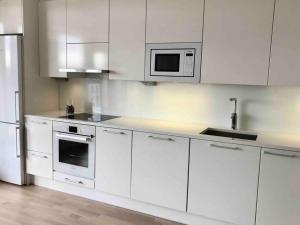 a white kitchen with white cabinets and a microwave at Tilava yksiö 35,5 m2 merenrannalla in Helsinki