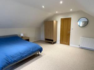 a bedroom with a blue bed and a mirror at Modern and cosy 4 bedroom home in the Mendip Hills, North Somerset in Axbridge